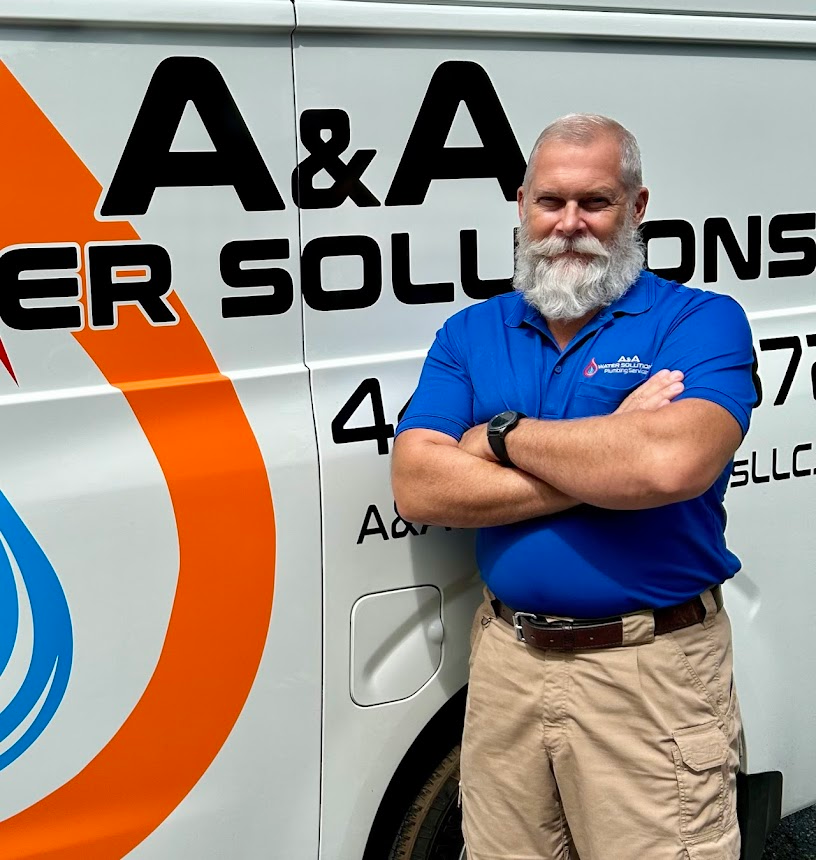 Anthony, one of the owners of AA Water Solutions, standing confidently in front of the branded company van, wearing a blue uniform with the company logo.