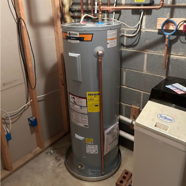 A water heater installed in a utility room, featuring copper piping connections and surrounding infrastructure in a partially finished space.